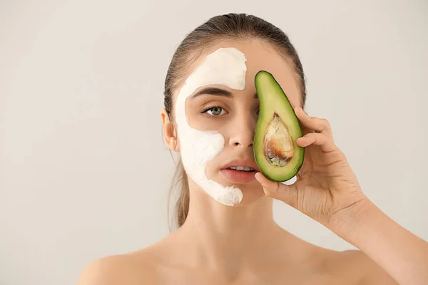 Hermosa Mujer Joven Con Máscara Facial Aguacate Sobre Fondo Claro —  Fotos de Stock