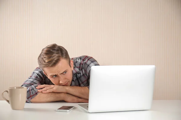 Stressed young man at table on light background