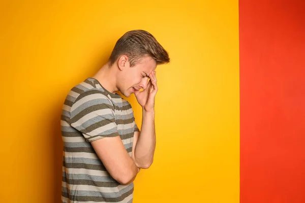 Portrait of stressed young man on color background