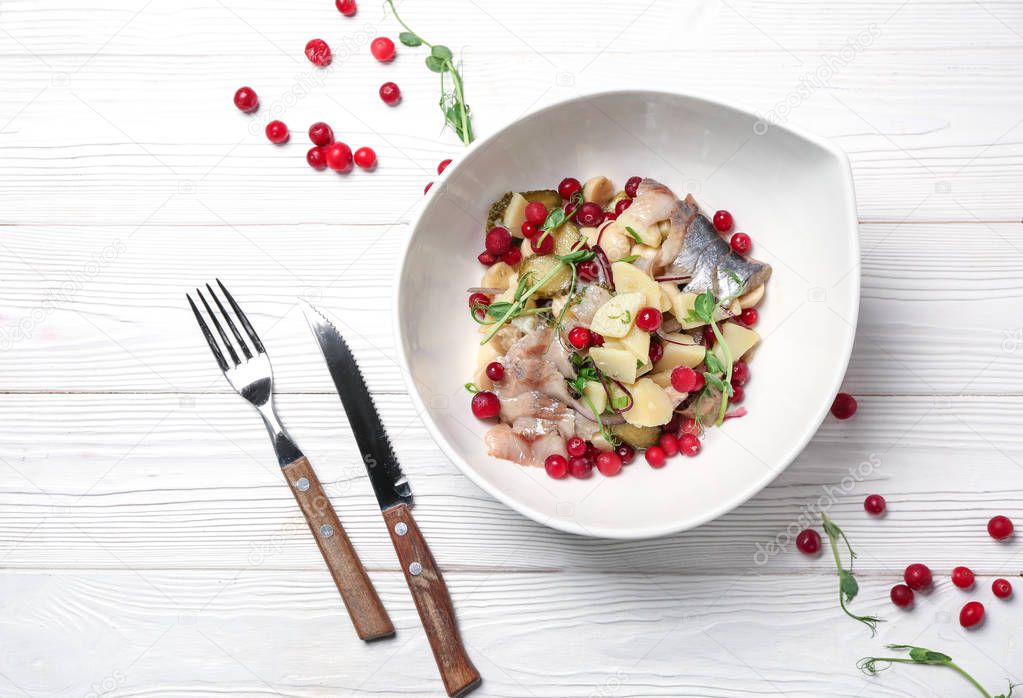 Plate with tasty fish salad on white wooden table