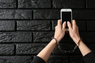 Kadın koyu arka plan üstünde hareket eden telefon ile kelepçeli. Bağımlılık kavramı