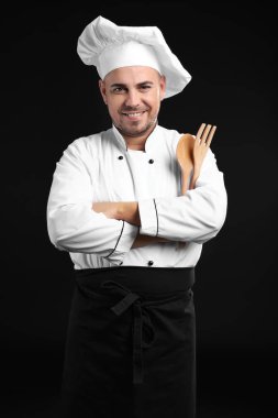 Koyu arka plan üzerinde mutfak gereçleri ile erkek Şef