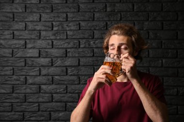 Adam siyah tuğla duvar yakınındaki bira içiyor. Alkolizm kavramı