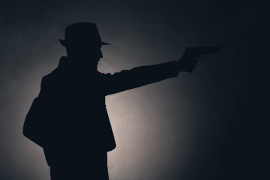 Dedektif koyu arka plan üzerinde silahla silüeti