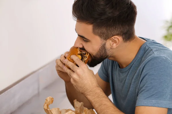 Jeune Homme Mangeant Hamburger Savoureux Dans Café — Photo