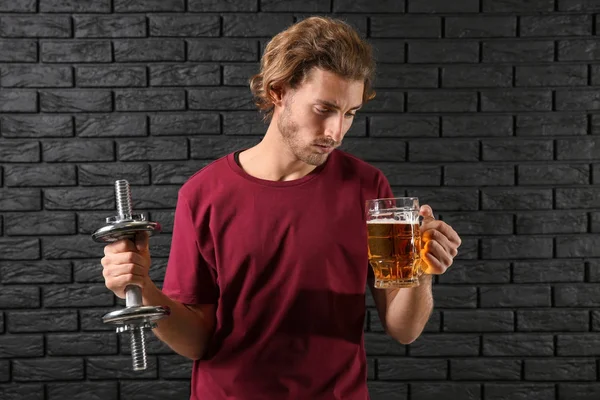 Young Man Dumbbell Mug Beer Black Brick Wall Concept Choice — Stock Photo, Image