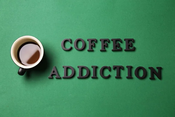 コーヒー色の背景上のテキストのコーヒー中毒のほとんど空のカップ — ストック写真