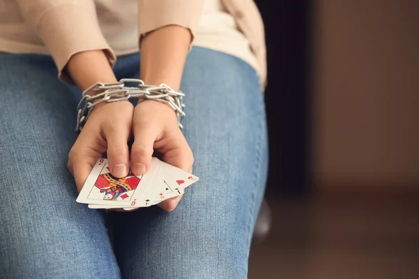 Woman with chained hands holding playing cards, closeup