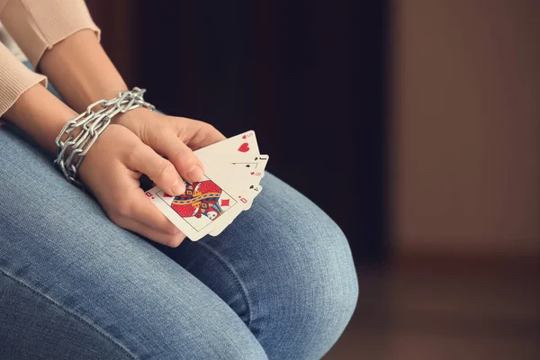 Woman with chained hands holding playing cards, closeup