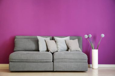 Modern rahat kanepe ve renk duvarının yakınında vazo