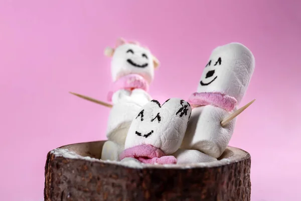 Cute snowmen made of tasty marshmallow on color background