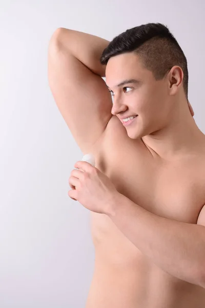 Jonge Man Met Behulp Van Deodorant Lichte Achtergrond — Stockfoto