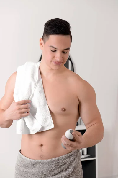 Young man with deodorant in bathroom