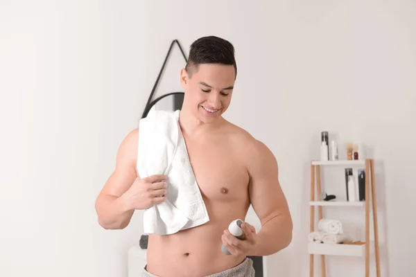 Young man with deodorant in bathroom