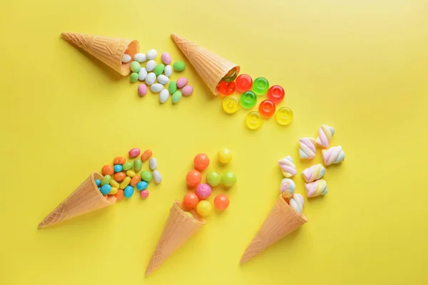 在颜色背景上与美味的糖果和华夫饼锥组成 — 图库照片