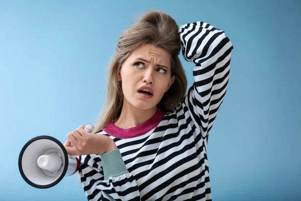 Thoughtful young woman with megaphone on color background