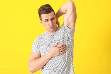 Yakışıklı genç duygu renk arka plan üzerinde ter kokusu. Deodorant kullanmanın kavramı