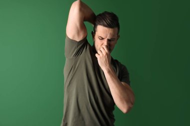 Yakışıklı genç duygu renk arka plan üzerinde ter kokusu. Deodorant kullanmanın kavramı