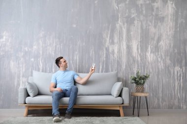 Klima kumanda evde koltukta oturan genç adam