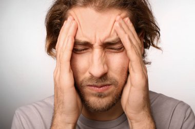 Genç adam açık renkli, closeup üzerinde baş ağrısı muzdarip