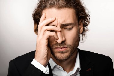Genç işadamı ışık arka plan üzerinde baş ağrısı muzdarip