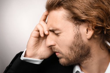 Genç işadamı ışık arka plan üzerinde baş ağrısı muzdarip