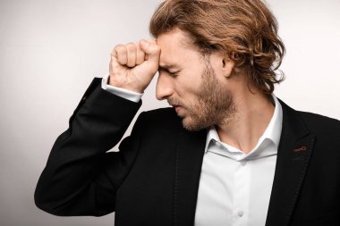 Genç işadamı ışık arka plan üzerinde baş ağrısı muzdarip