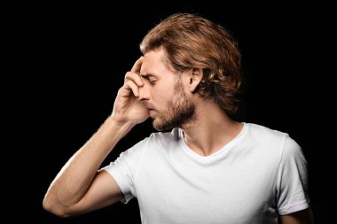 Genç adam koyu arka plan üzerinde baş ağrısı muzdarip