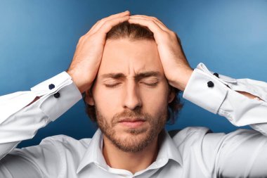 Arka planda baş ağrısı çeken genç bir adam