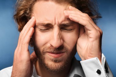 Genç adam renk arka plan, closeup üzerinde baş ağrısı muzdarip