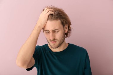 Arka planda baş ağrısı çeken genç bir adam