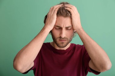 Arka planda baş ağrısı çeken genç bir adam