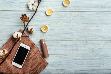 Pamuk çiçekler, mumlar ve ahşap arka plan üstünde hareket eden telefon ile kompozisyon