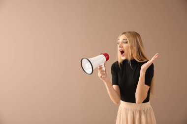 Emotional young woman with megaphone on color background clipart