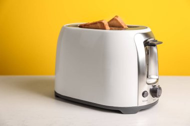 Tost makinesiyle renk arka plan karşı masada ekmek dilimleri