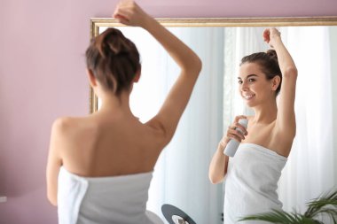 Deodorant ayna önünde kullanan genç kadın
