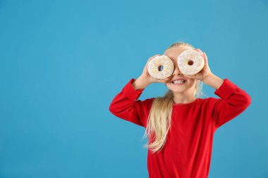 Renk arka plan üzerinde çörek ile sevimli küçük kız