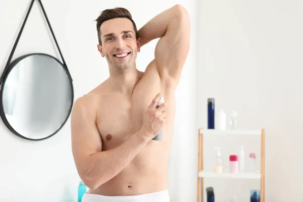 Handsome young man with deodorant in bathroom