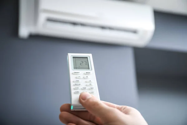 Male hand with air conditioner remote control