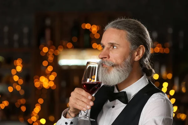 Senior man drinking wine in bar