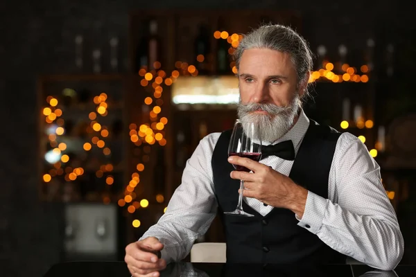 Senior man drinking wine in bar