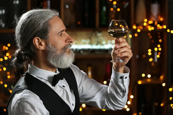 Senior man drinking wine in bar