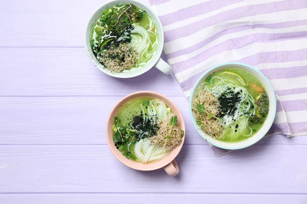 Tasty Chinese soup in cups on wooden table