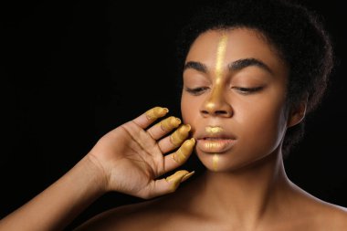 Siyah arka plan karşı vücudu üzerinde altın boya ile Afrikalı-Amerikalı kadın