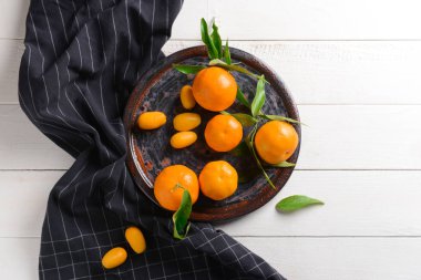 Plate with tasty tangerines on table clipart