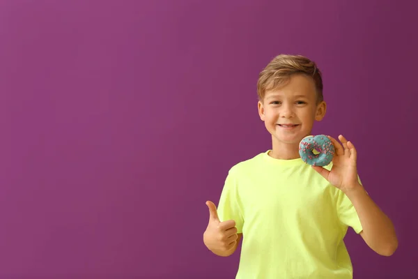 Симпатичный Маленький Мальчик Пончиком Показывает Большой Палец Вверх Цветном Фоне — стоковое фото