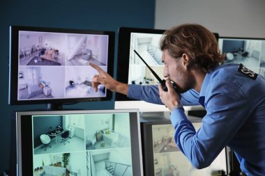 Güvenlik görevlisi gözetleme odasındaki modern güvenlik kameralarını izliyor.