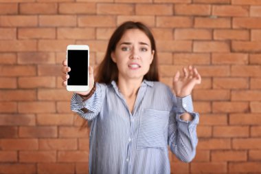 Çalışmayan cep telefonu tuğla zemin üzerine genç kadınla vurguladı