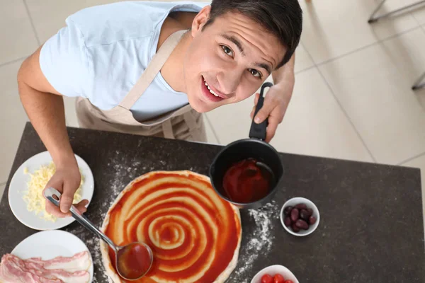 Junger Mann Trägt Sauce Auf Pizzateig Tisch Auf Draufsicht — Stockfoto