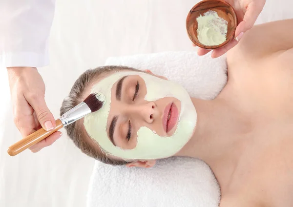 Cosmetologist Aplicando Máscara Rosto Jovem Mulher Salão Beleza — Fotografia de Stock